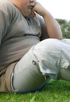 obese child sits on grass