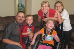 adult male, young boy, girl in wheelchair, adult female behind wheelchair, and pre-teen girl. All family wearing ties.